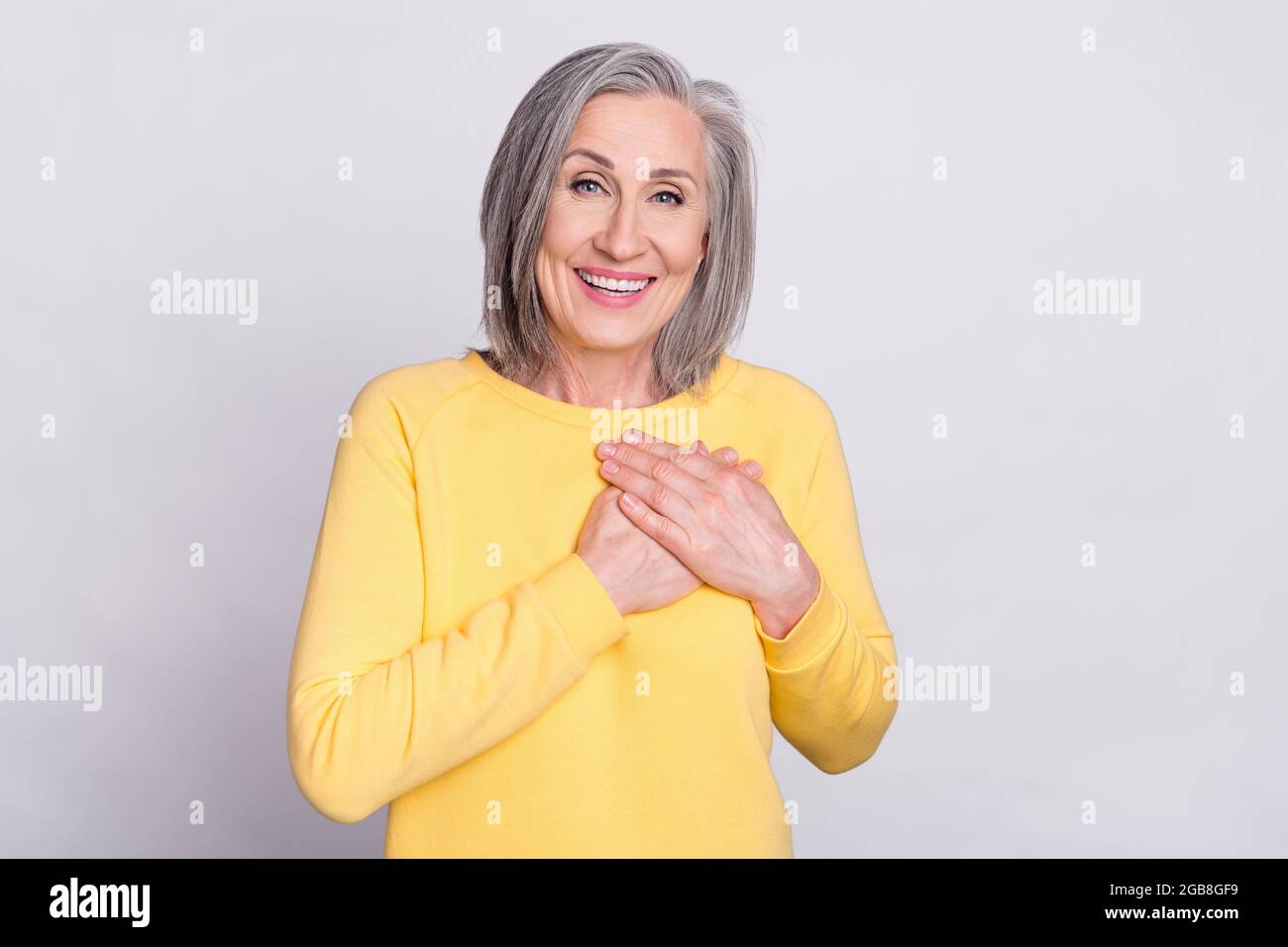 Photo of happy cheerful excited lovely mature woman hold hands chest ...