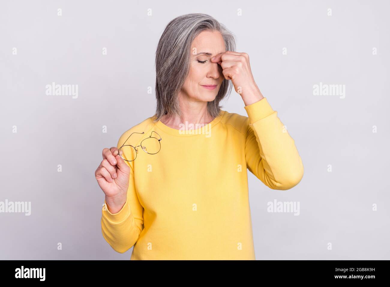 Photo of unhappy sad stressed mature woman suffering headache overworked isolated on grey color background Stock Photo