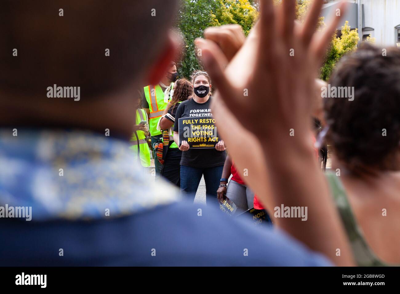 Washington, DC, USA, 2 August 2021.  Pictured: A protester with a sign awaits arrest during a civil disobedience action on Constitution Avenue, while other protesters sing and dance in support.  The Moral Monday March was sponsored by the Poor People’s Campaign, Kairos Center, and Repairers of the Breach.  Credit: Allison Bailey / Alamy Live News Stock Photo