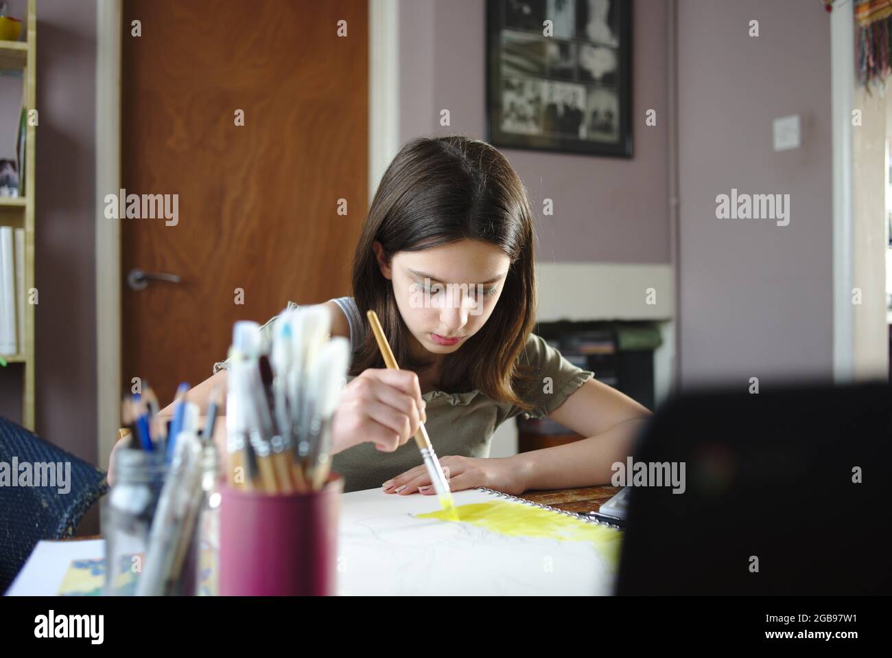 Young teenage girl painting, participating in an online art class