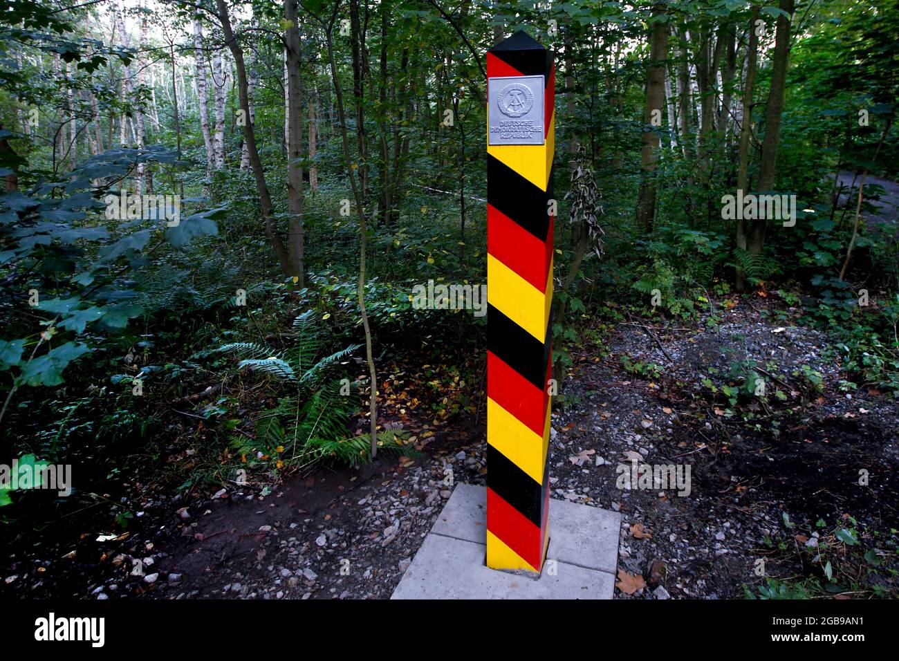 Border column with GDR coat of arms in the forest, border post in the Harz Mountains, hammer and compass, column path, perforated plate path Stock Photo