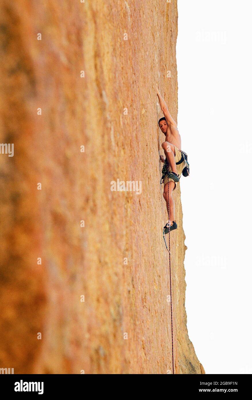 A young man rock climbing on a vertcal cliffside. Stock Photo
