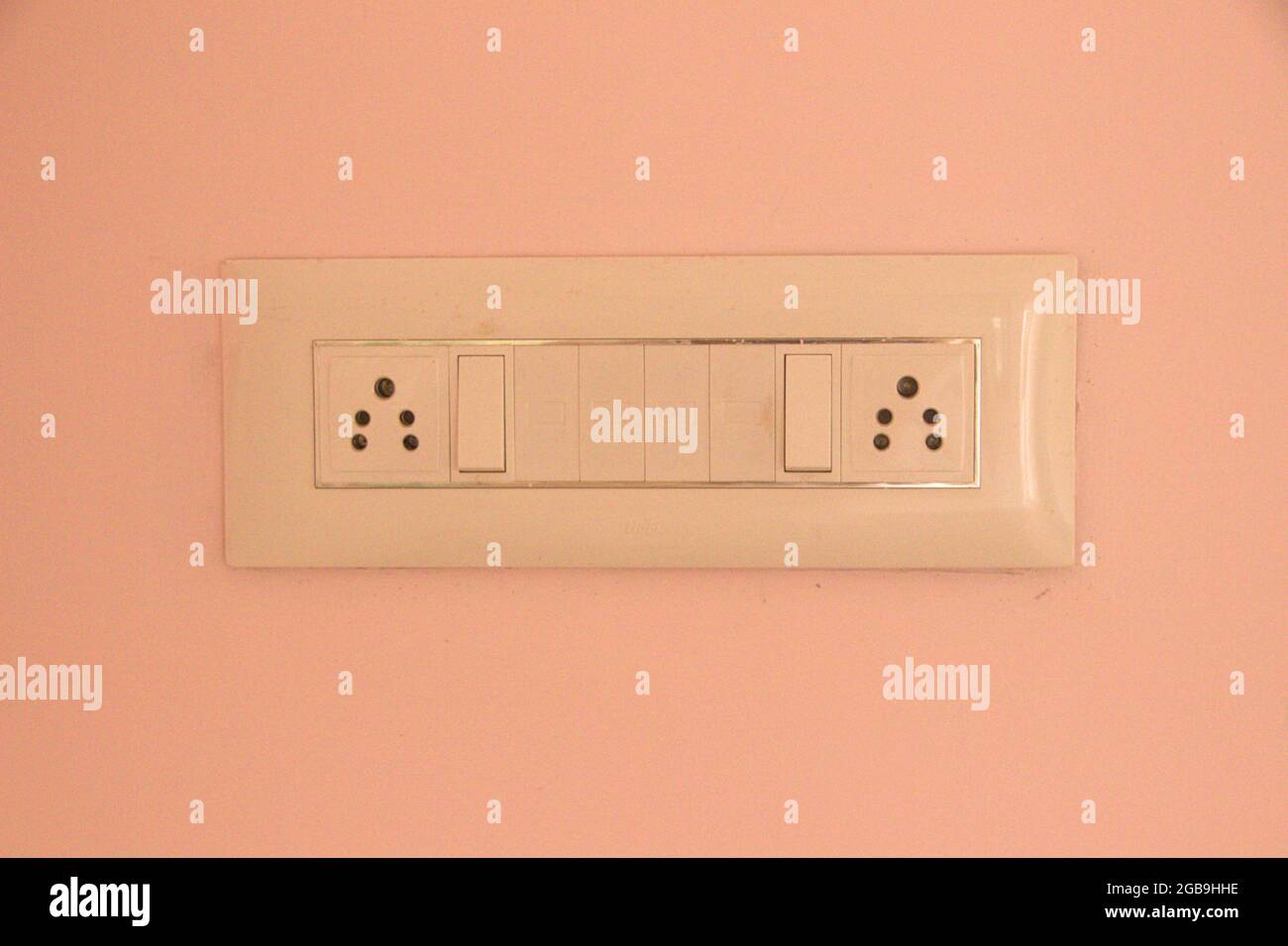 View of electrical switch board panel with two plug sockets on light brown wall Stock Photo