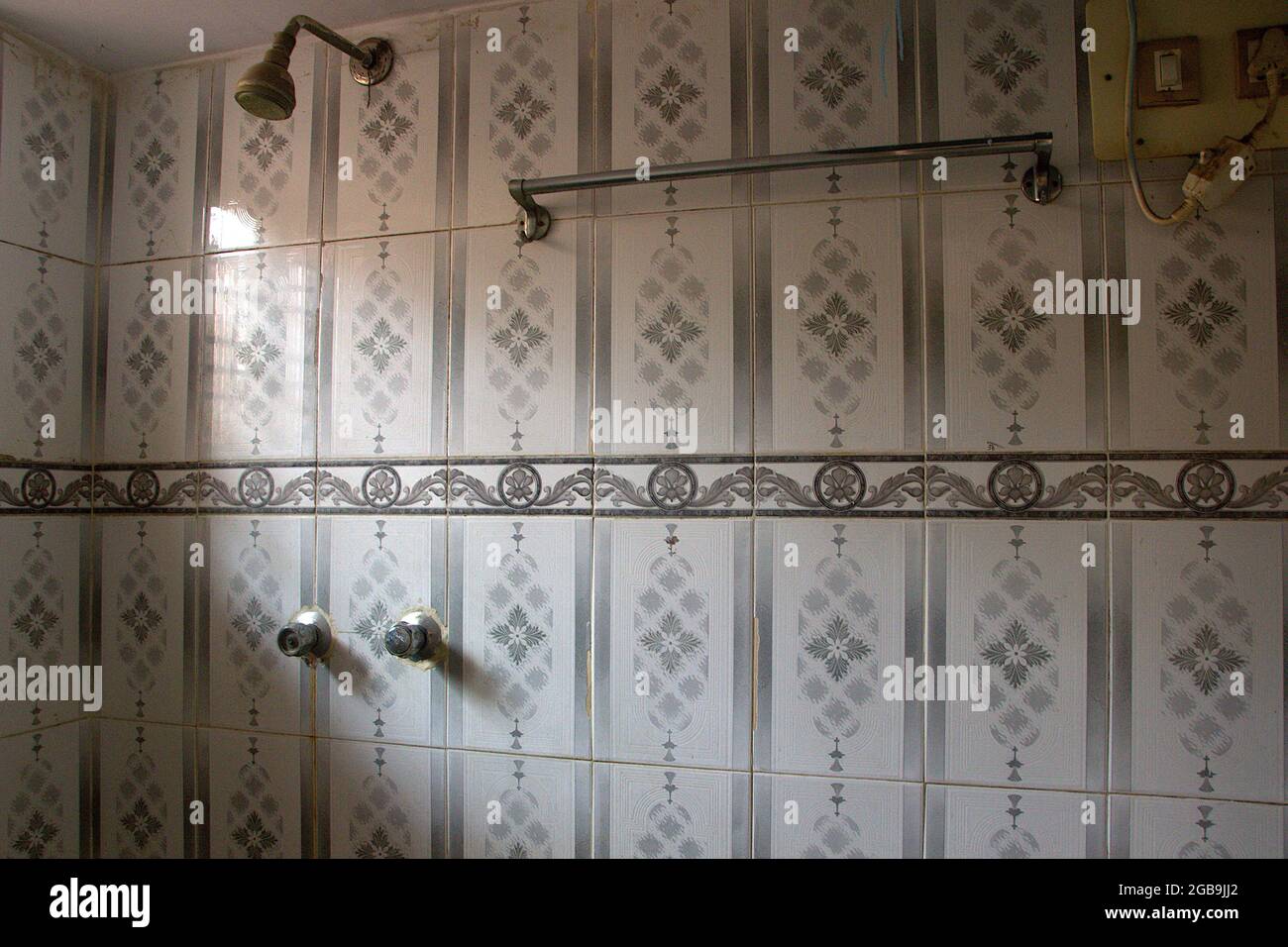 View of shower fitting, knobs and towel holder fitted on tiled wall of