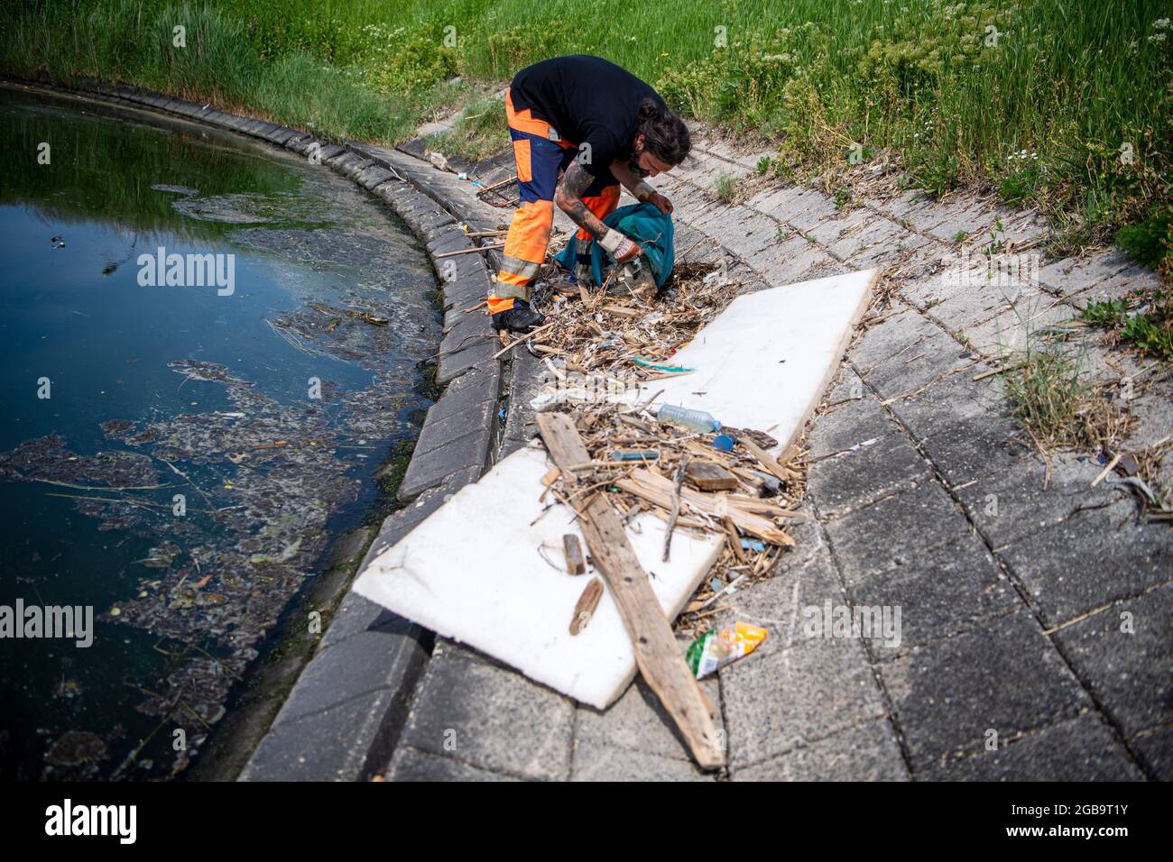 Emden, Germany. 09th June, 2021. Björn Fuhlendorf, NPorts employee, collects rubbish that has washed up at the port. Several cities in Lower Saxony are planning to equip their harbours with the so-called marine litter bins in the near future. A submersible pump underneath a basket permanently sucks in water. Flotsam floating on the water surface nearby is sucked in and falls into the collection net. The water flows back into the harbor basin. Credit: Sina Schuldt/dpa/Alamy Live News Stock Photo