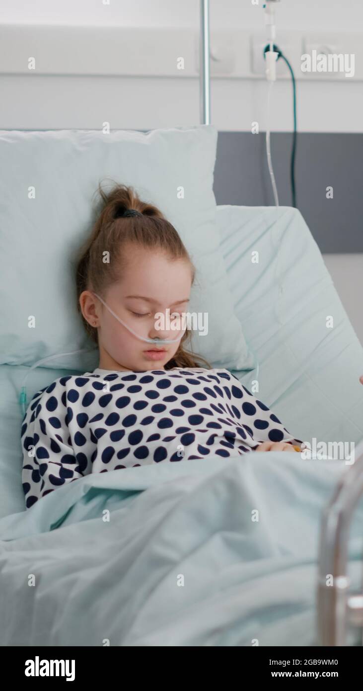 Worried mother sitting beside little daughter praying while sleeping