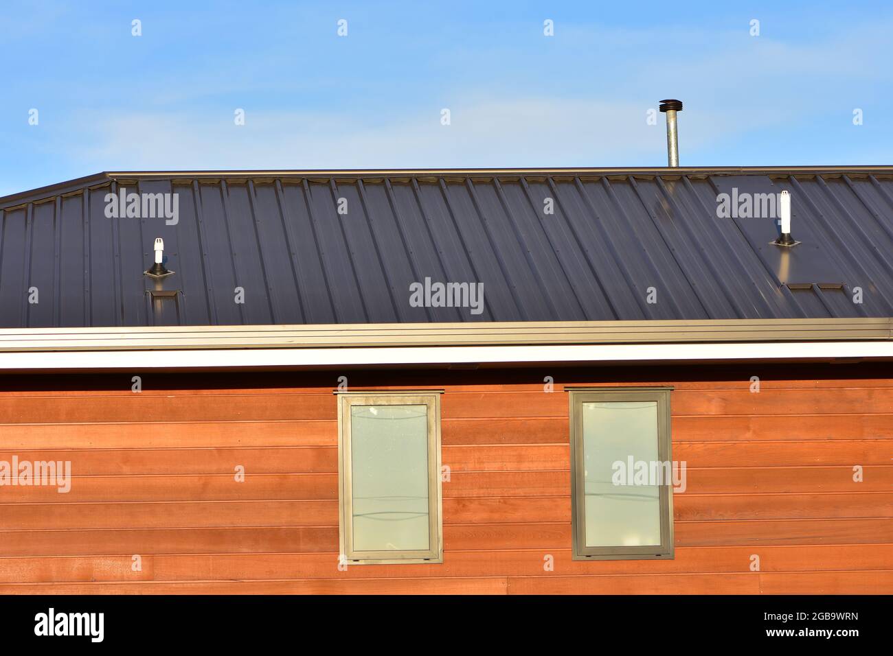 Detail of modern house with cedar cladding and corrugated metal roof. Stock Photo