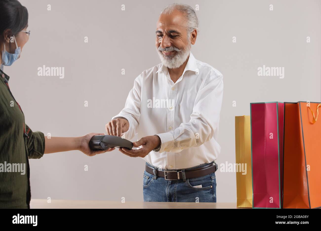 AN OLD MAN HAPPILY USING DEBIT CARD TO DO SHOPPING Stock Photo