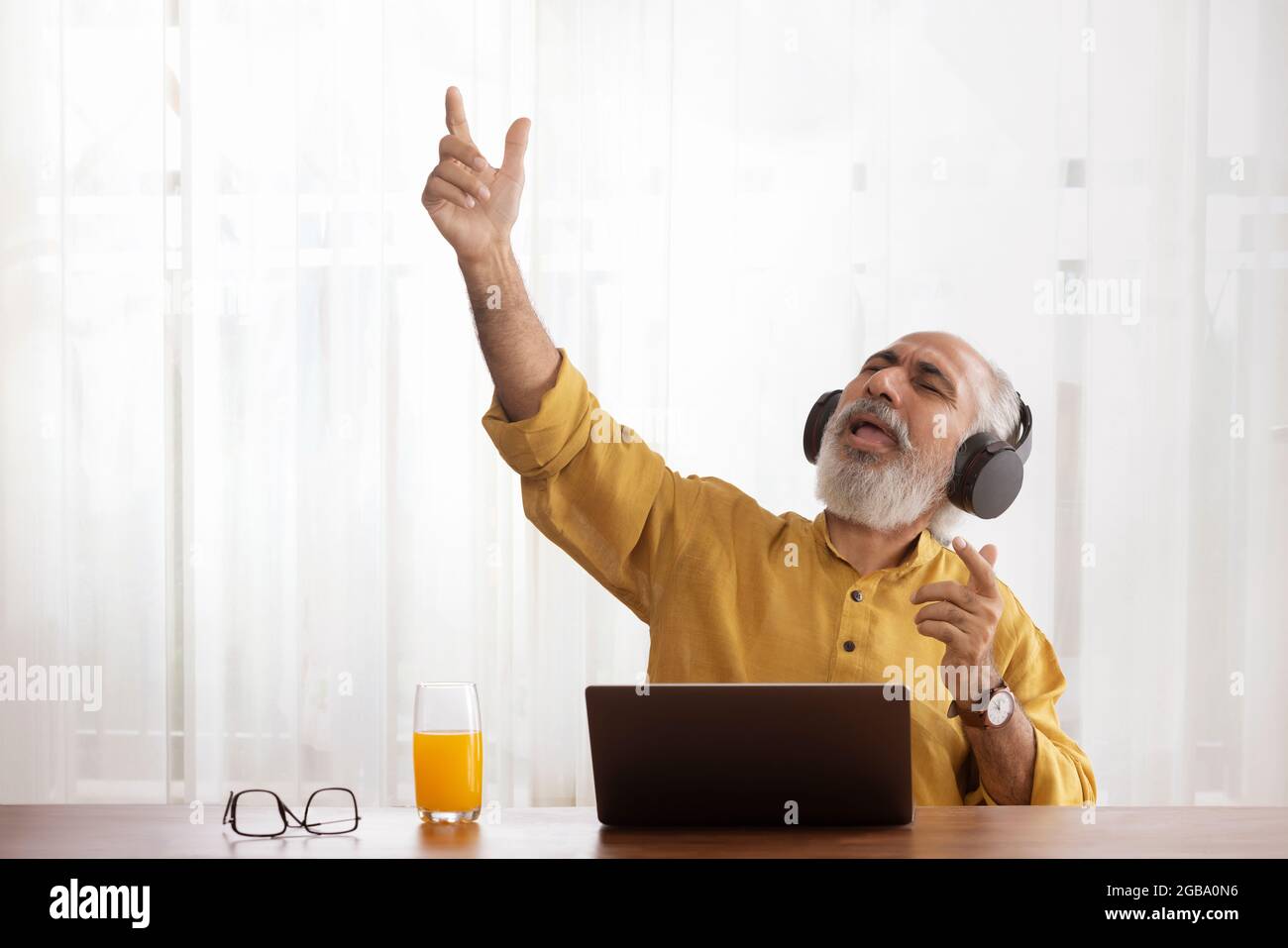 A HAPPY OLD MAN CHEERFULLY SINGING WHILE LISTENING TO MUSIC Stock Photo