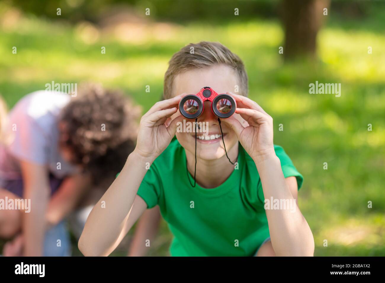 Boy looking through binoculars in nature Stock Photo