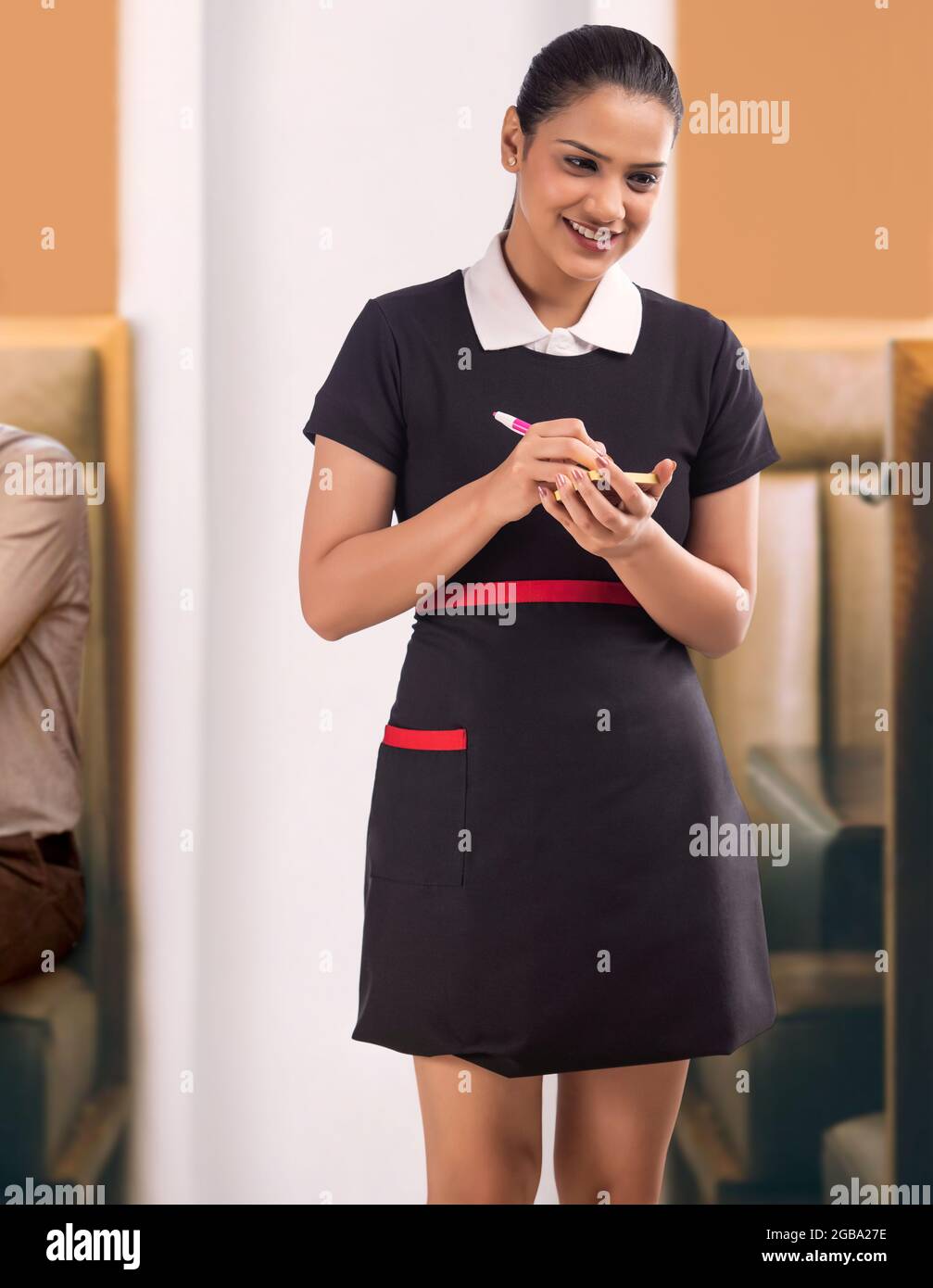 A HAPPY WAITRESS TAKING DOWN ORDERS WHILE WORKING Stock Photo