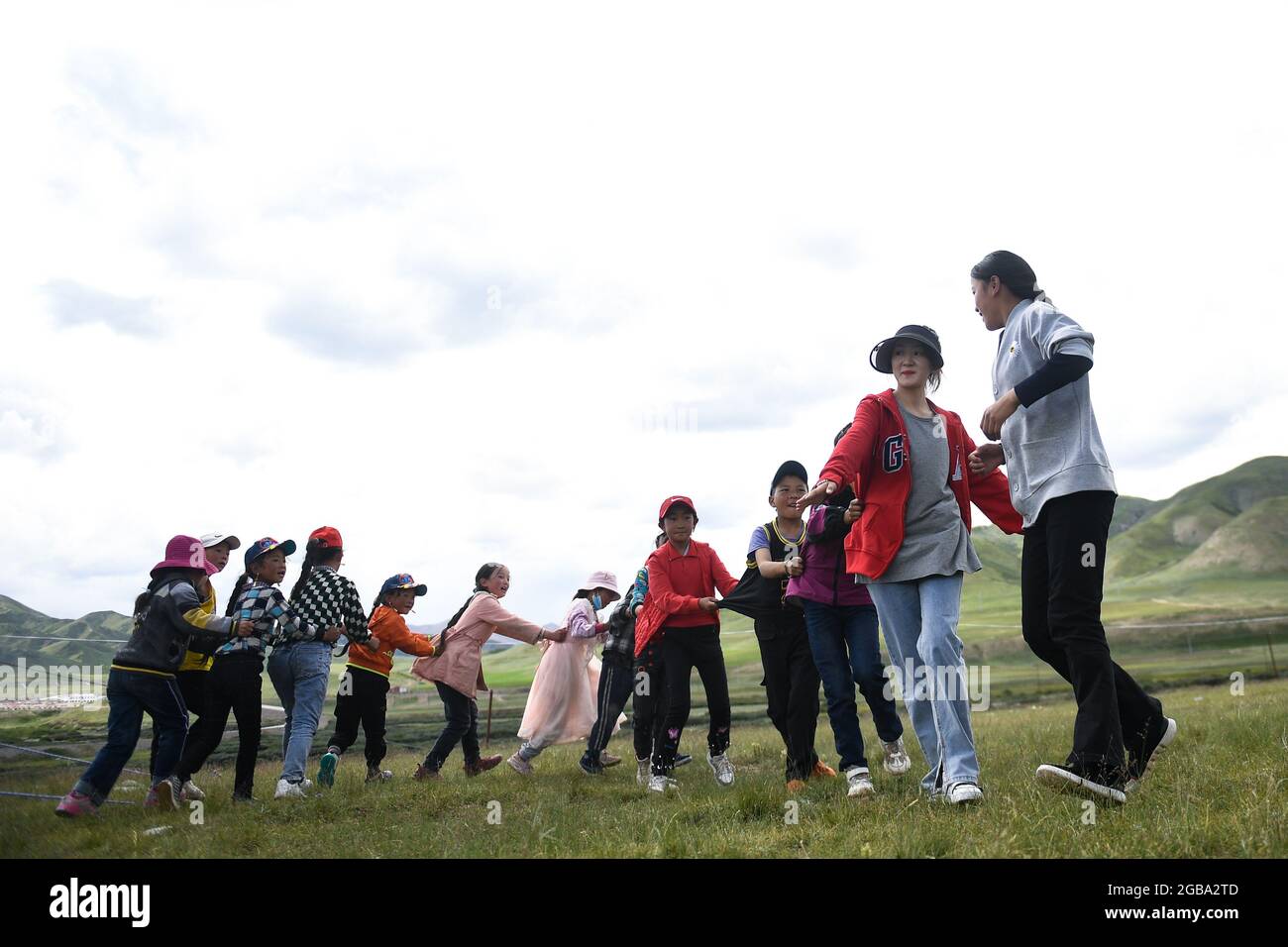 210803) -- GOLOG, Aug. 3, 2021 (Xinhua) -- Children play a game guided by  college student volunteers at a daycare center in Nyainca Village of Maqen  County, Golog Tibetan Autonomous Prefecture, in