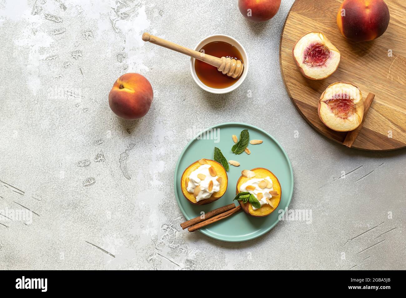 Baked peaches on a plate with mint leaf, cinnamon, non-dairy cream cheese, honey, and almond flakes. Stock Photo