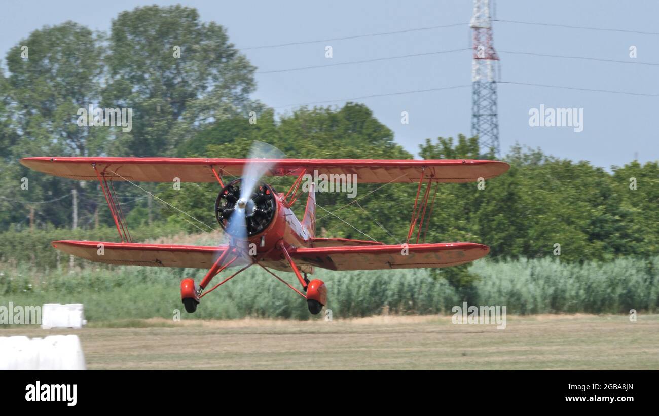 Ferrara Italy JUNE, 27, 2021 Frontal view close up of a red 1930s biplane with propeller and radial engine take off. WACO UPF7 Stock Photo