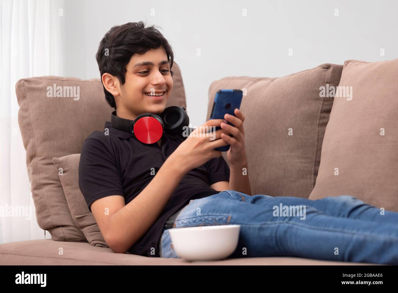 A TEENAGER SMILING AND USING MOBILE PHONE AT HOME Stock Photo - Alamy