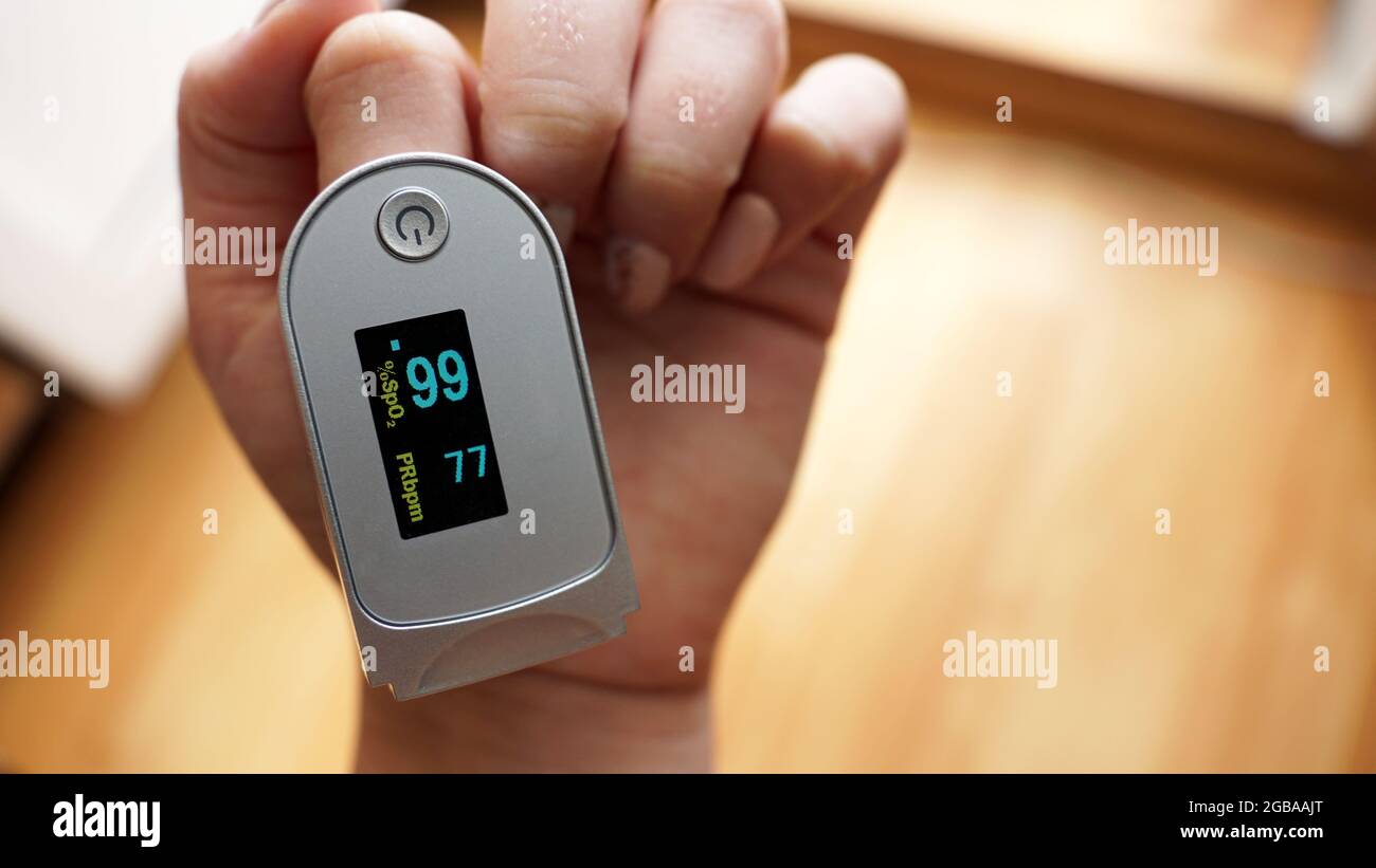 Pulse oximeter on finger showing oxygen saturation and heart rate