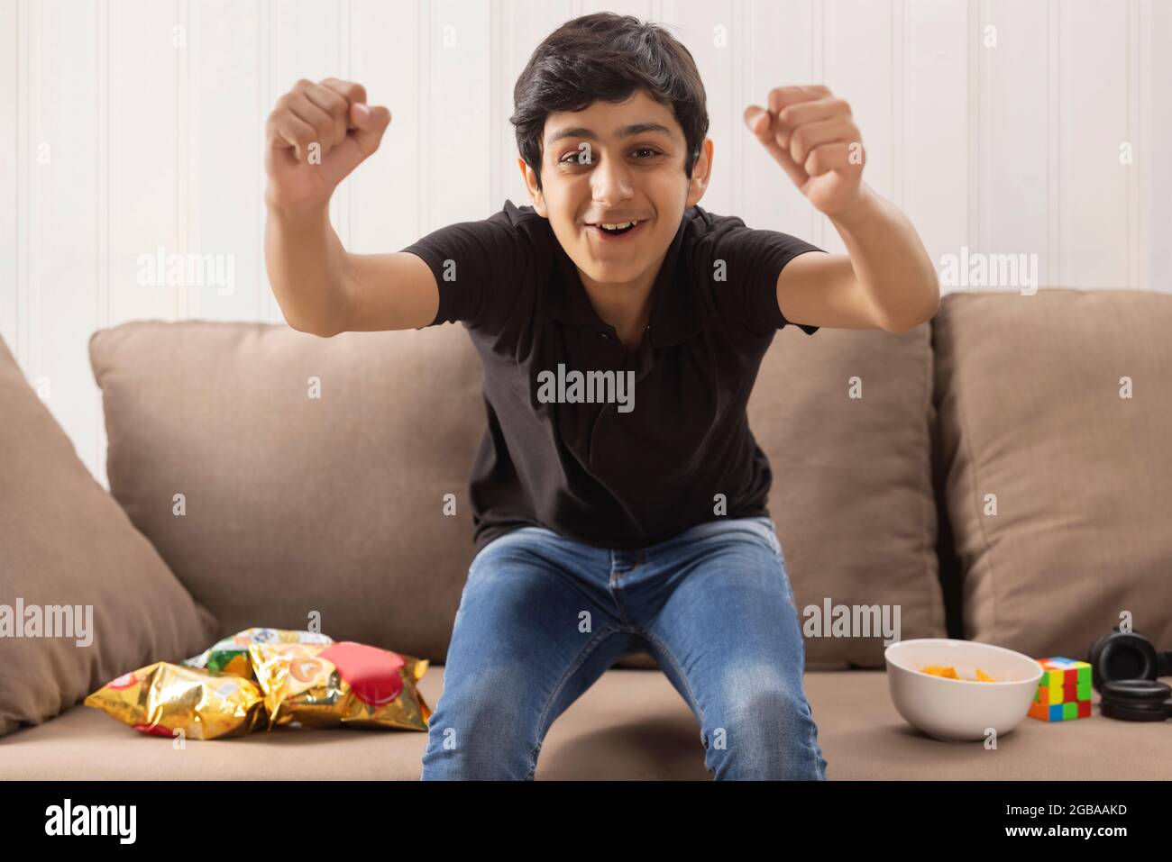 A TEENAGE BOY EXCITEDLY LOOKING AT CAMERA WHILE EATING SNACKS Stock Photo