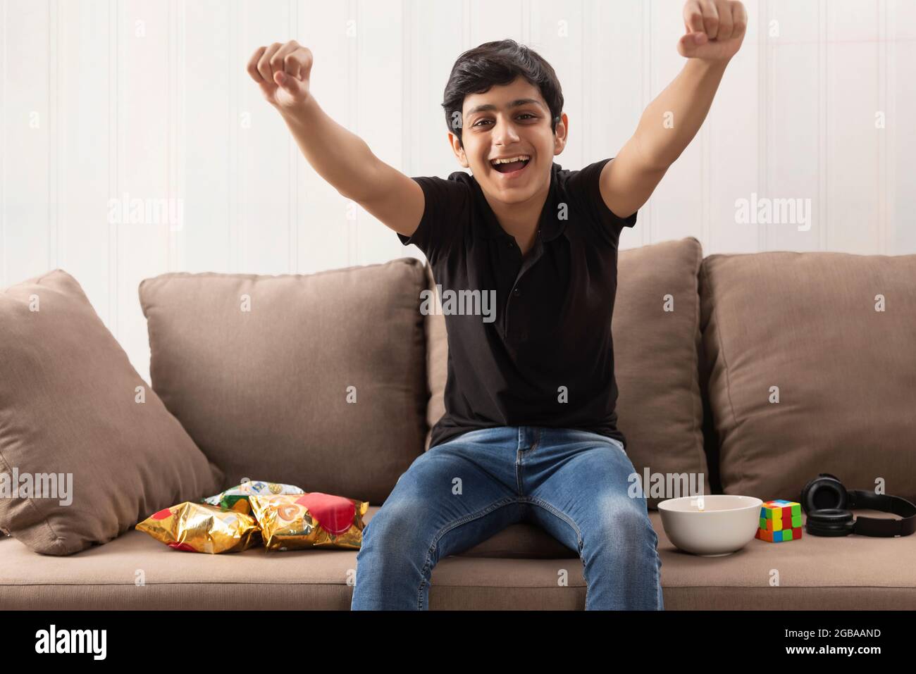 A TEENAGE BOY HAPPILY CHEERING WHILE SITTING IN FRONT OF CAMERA Stock Photo