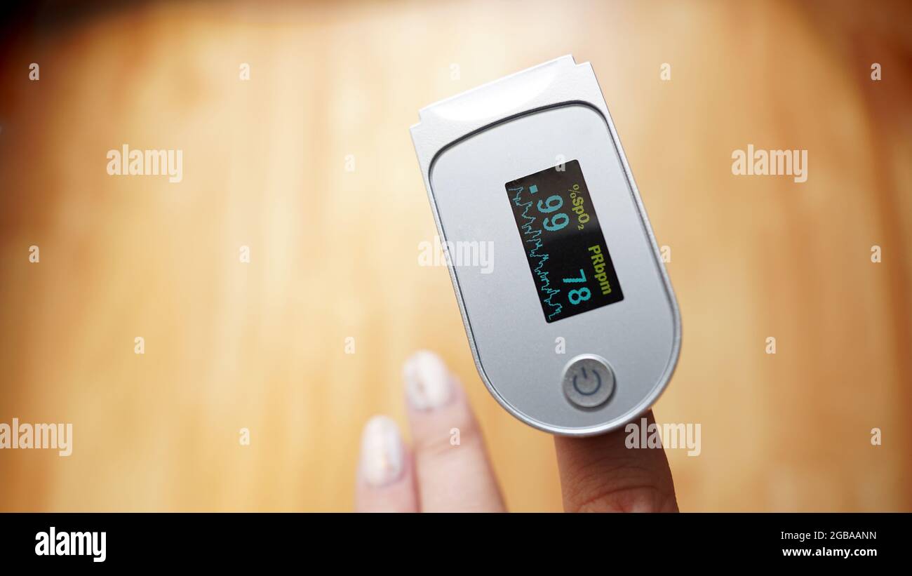 Pulse oximeter on finger showing oxygen saturation and heart rate