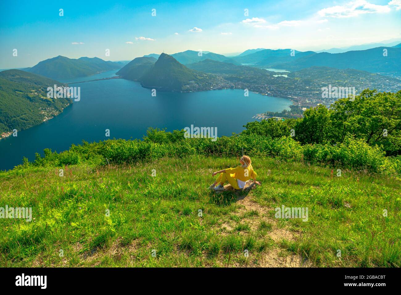 Woman on top of Lugano Swiss city by Lugano Lake in Switzerland. Aerial view lookout from Monte Bre Mount. Lugano cityscape with San Salvatore mount Stock Photo