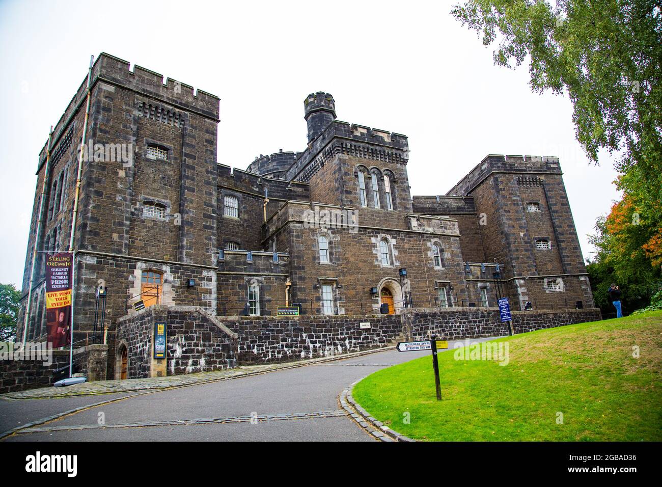 Green meadow with a dark stone palace in the background and a large tree. Stock Photo