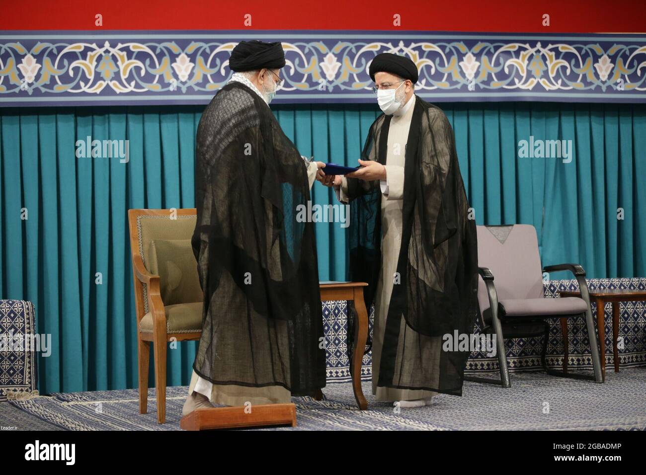 Tehran, Tehran, Iran. 3rd Aug, 2021. A handout picture made available by Iran's Supreme Leader Office shows Iranian supreme leader Ayatollah ALI KHAMENEI (L) handing over the presidential precept to new Iranian president EBRAHIM RAISI (R), in Tehran, Iran, 03 August 2021. Iranian presidents are first approved by the supreme leader, who according to the constitution is the actual head of state, and then take the oath before parliament. Ebrahim Raisi has been inaugurated as the new president of the Islamic Republic of Iran on 03 August 2021, as the country is facing an economic crisis along wit Stock Photo