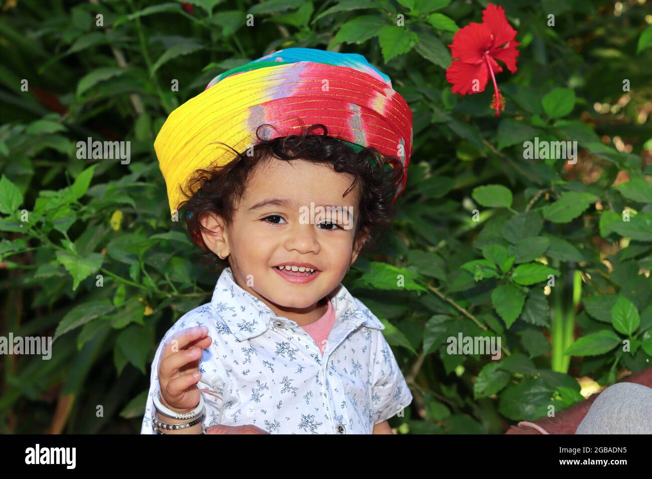 Close-up portrait of A small indian hindu child wearing a turban in the garden and smiling and looking at the camera. A little Asian boy smiling in th Stock Photo