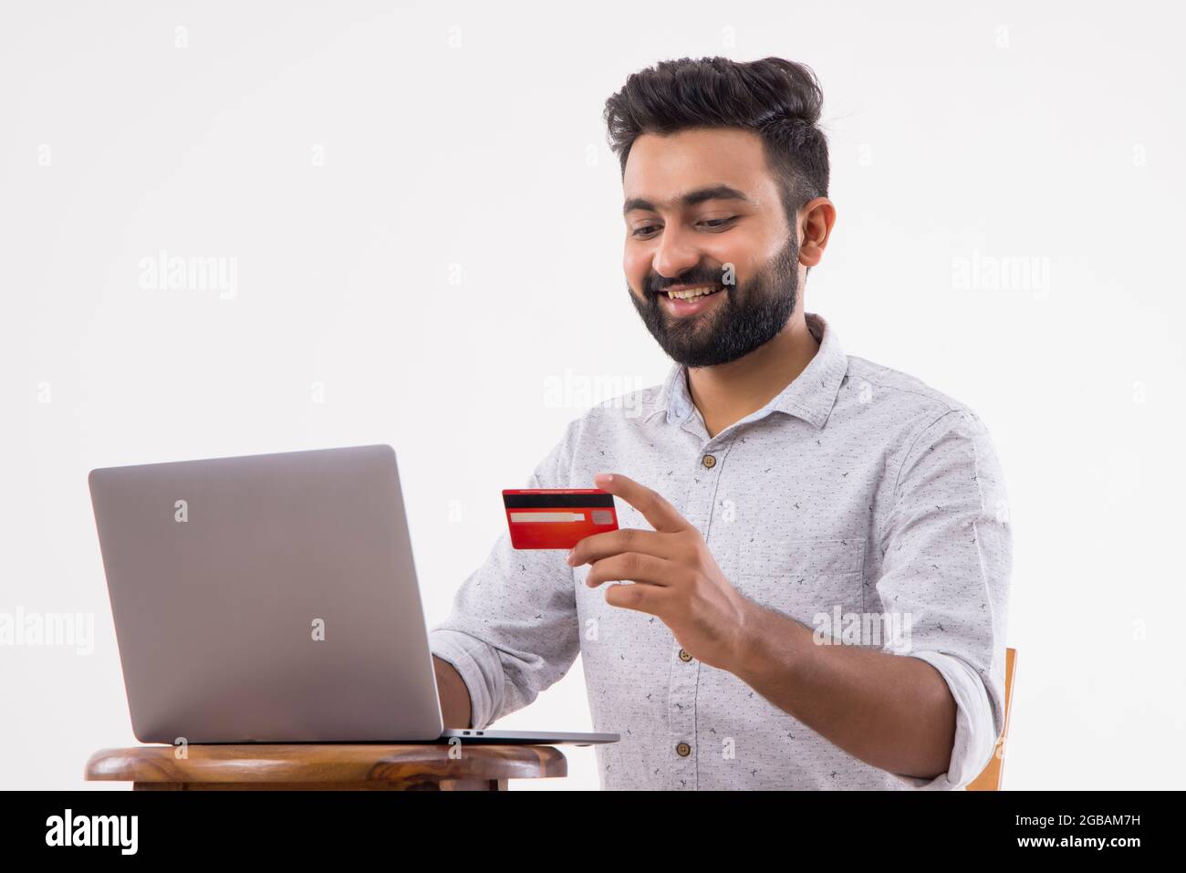 A BEARDED MAN HAPPILY DOING ONLINE TRANSACTIONS Stock Photo