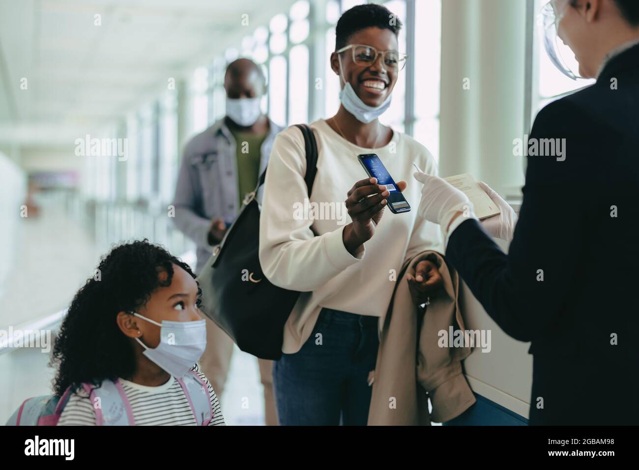 Woman traveler with daughter in face masks showing digital boarding