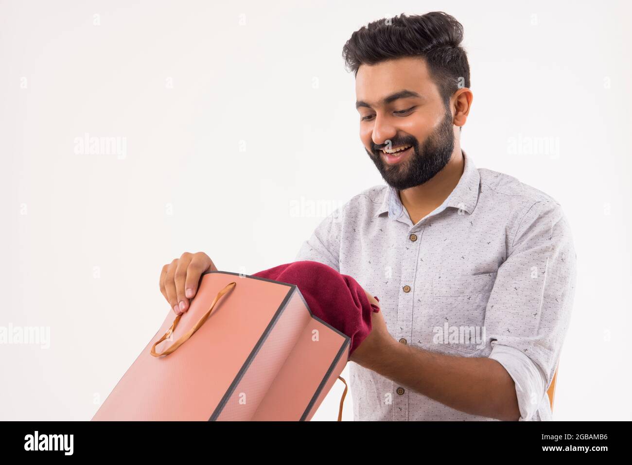 A BEARDED YOUNG MAN LOOKING AT NEWLY PURCHASED CLOTHES Stock Photo