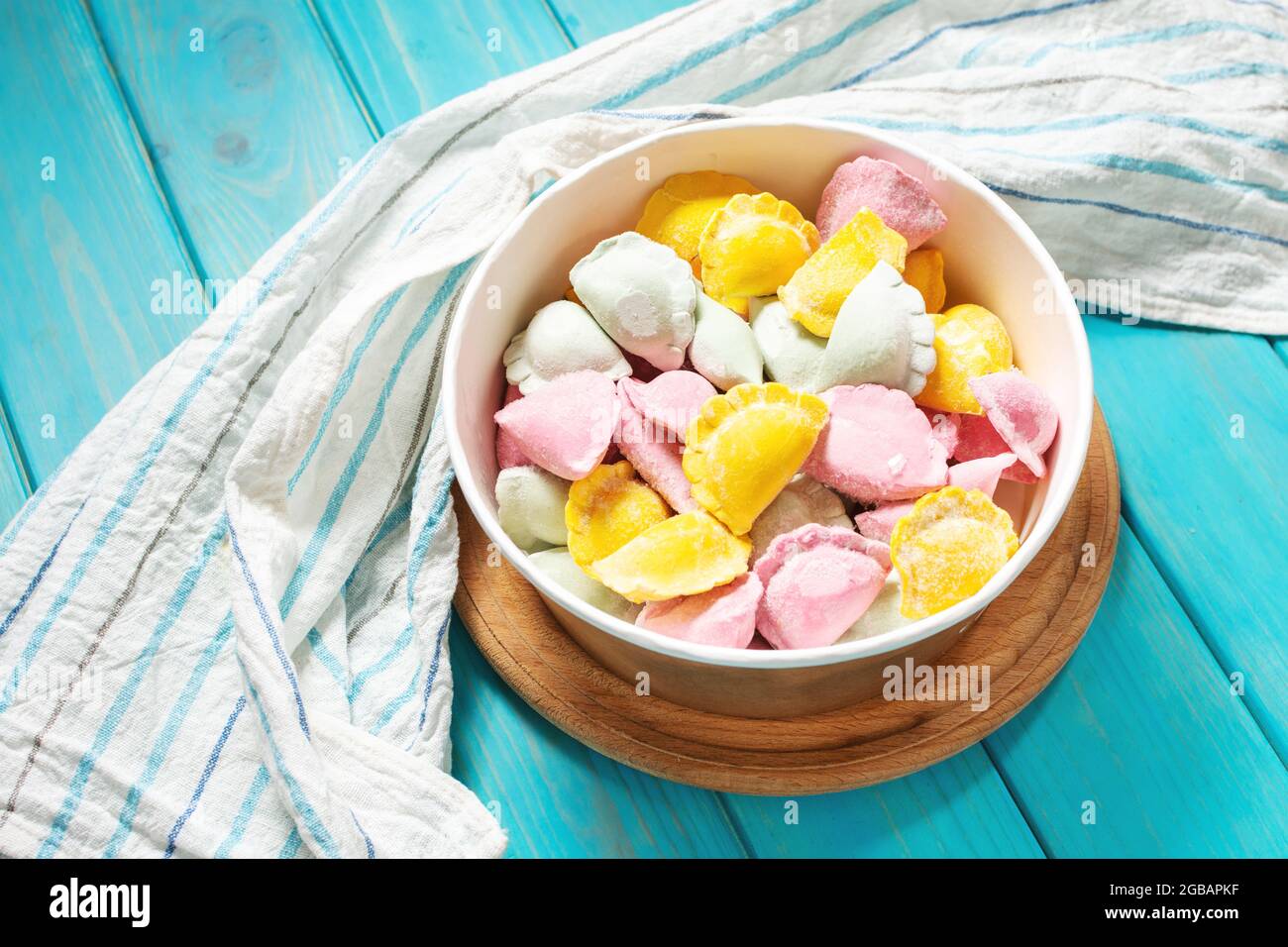 Multi colored dumplings from color dough stuffed with meat on a blue wooden background Stock Photo