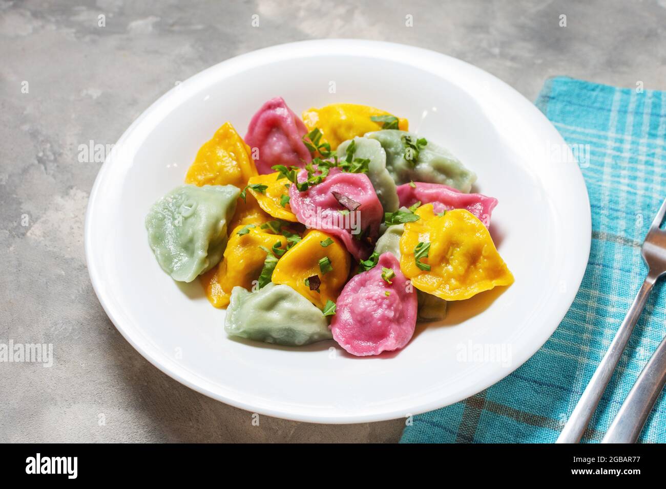 Multi colored dumplings from color dough stuffed with meat on a concrete background Stock Photo