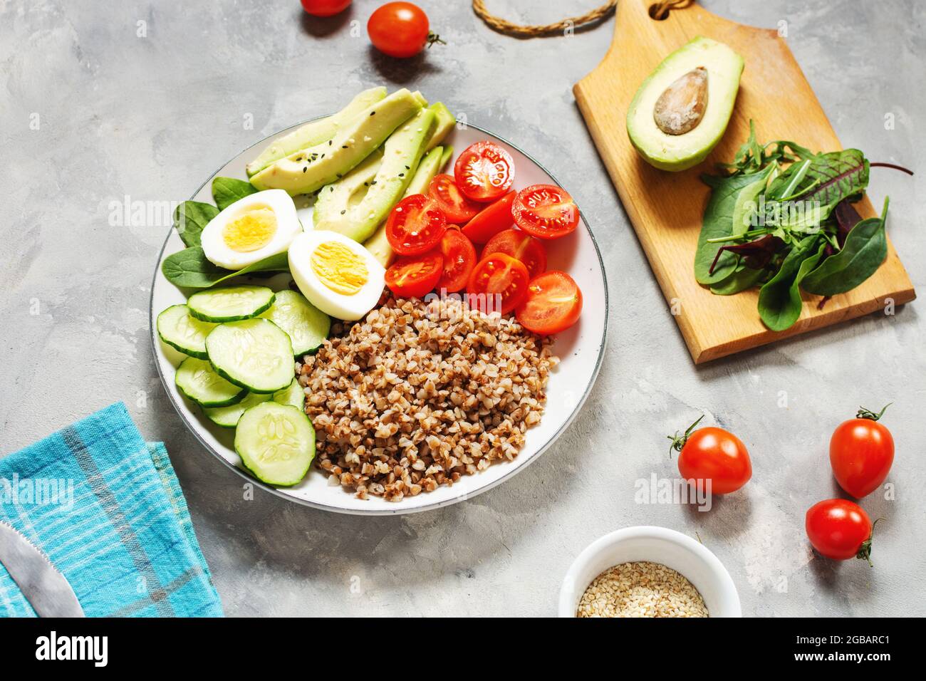Vegan lunch bowl with avocado, egg, cucumber, tomato and buckwheat on a concrete background Stock Photo