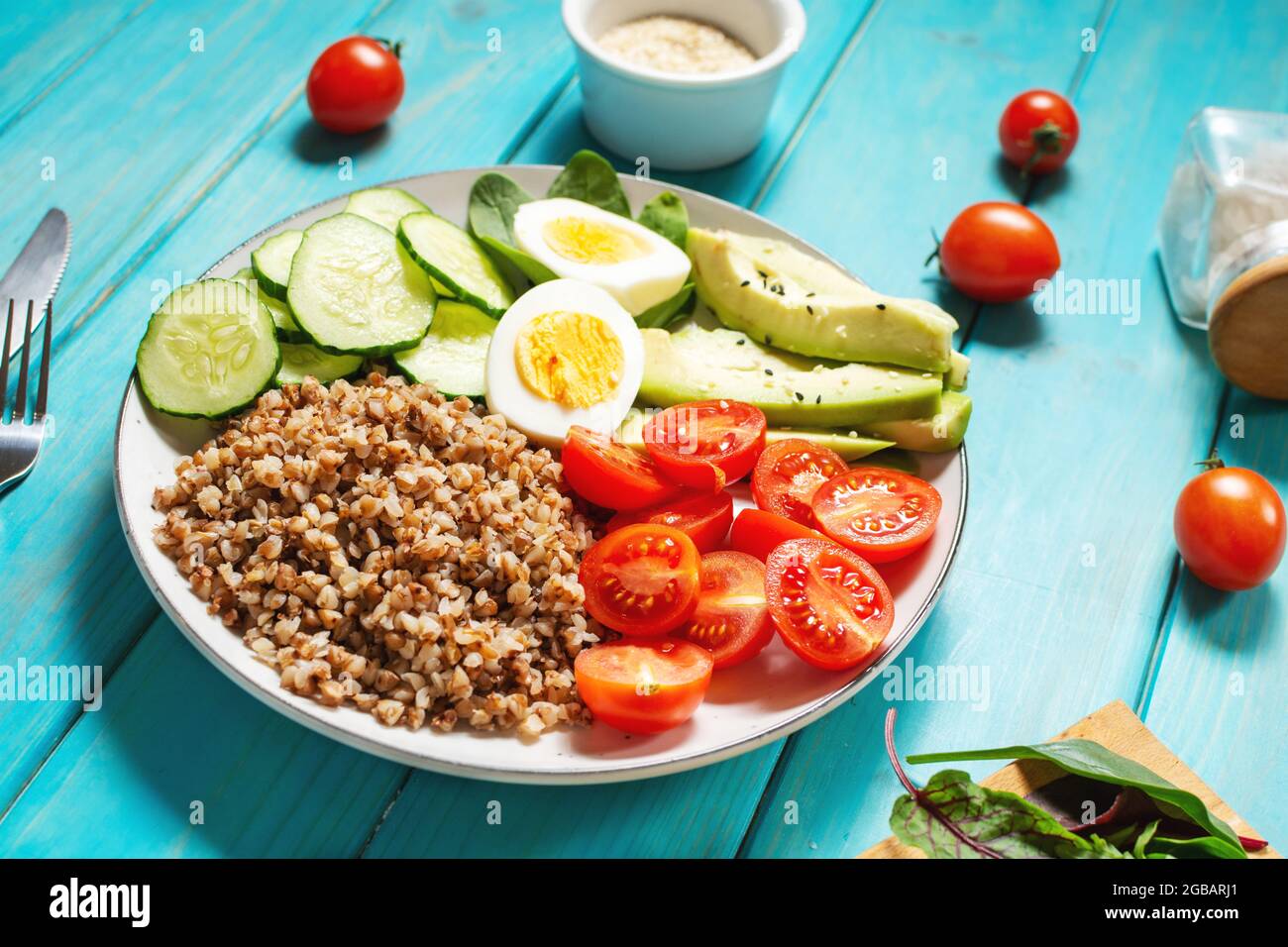 Vegan lunch bowl with avocado, egg, cucumber, tomato and buckwheat on wooden background Stock Photo