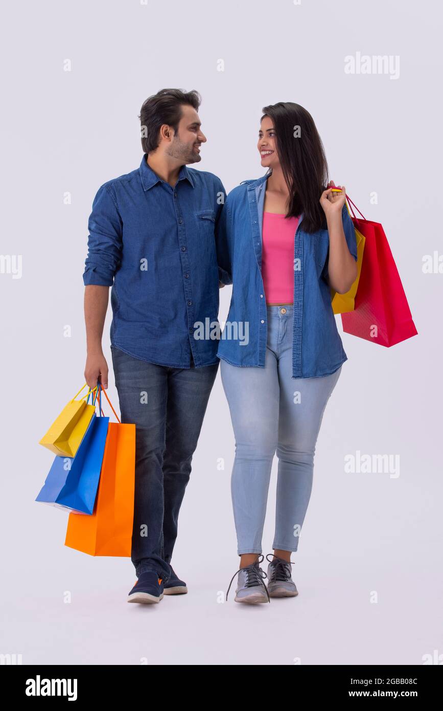 A young man and woman looking at each other while holding colorful carrybags. Stock Photo