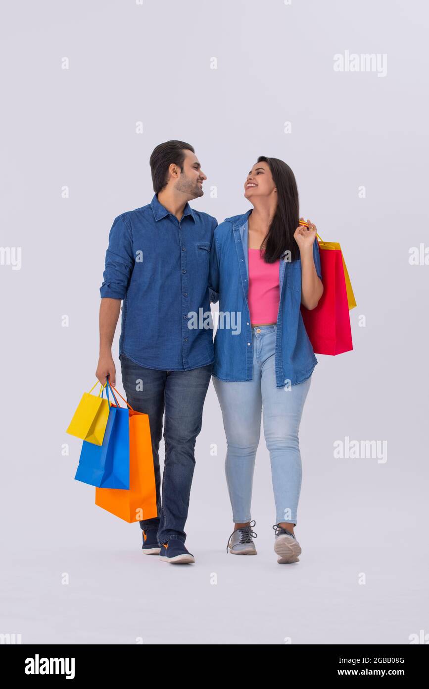 A young man and woman looking at each other while holding colorful carrybags. Stock Photo