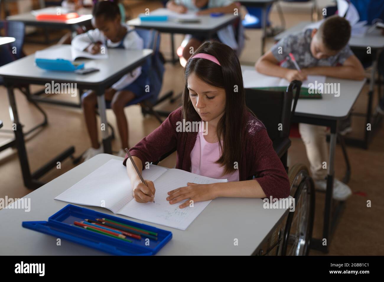 Caucasian girl studying while sitting on her desk in the class at ...