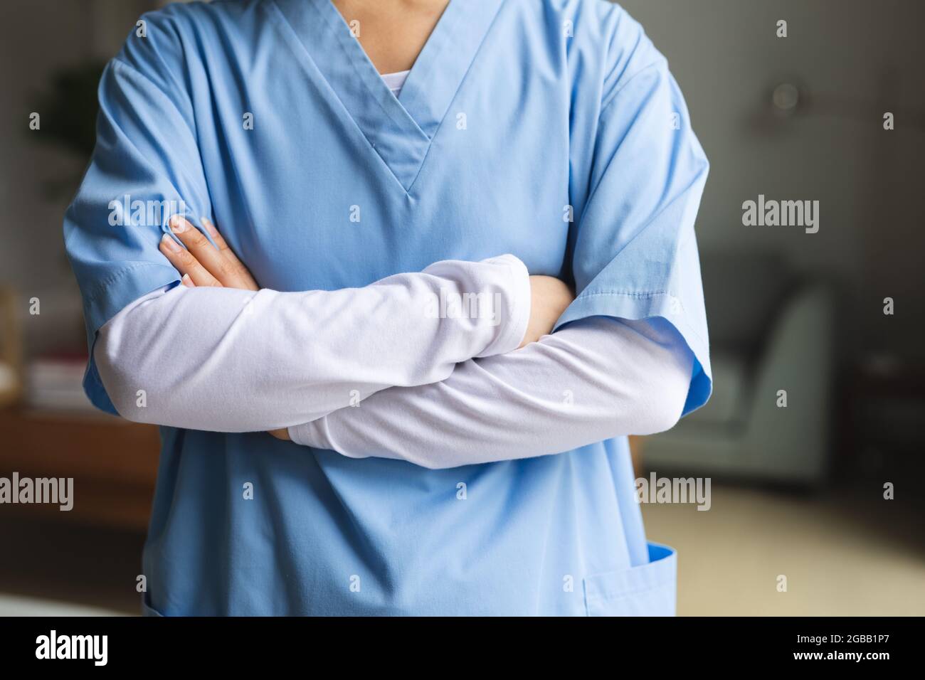 Asian female physiotherapist standing with arms crossed at home before treatment Stock Photo