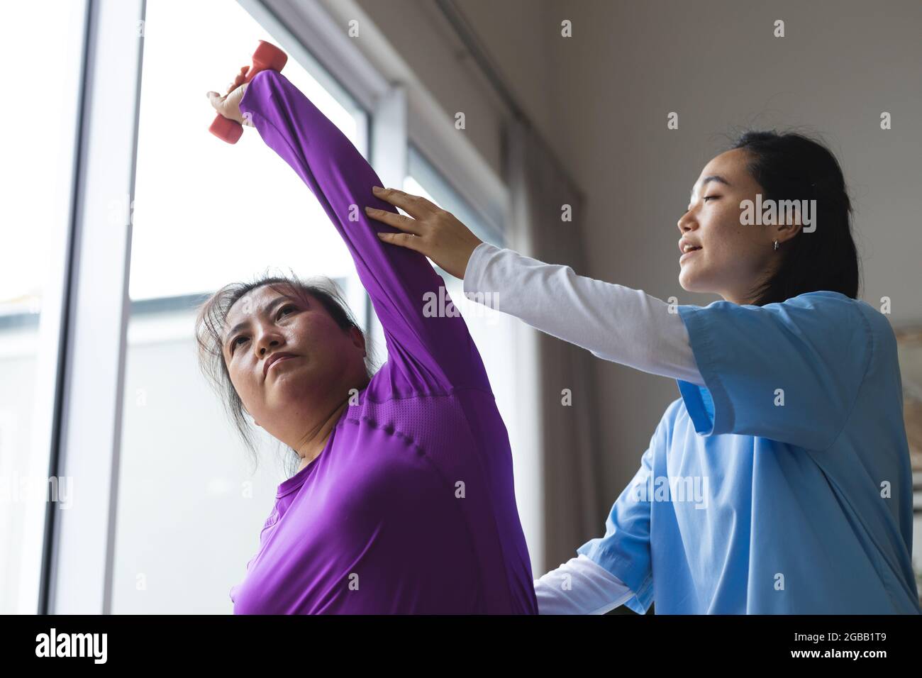 Asian female physiotherapist treating asian female patient at her home Stock Photo