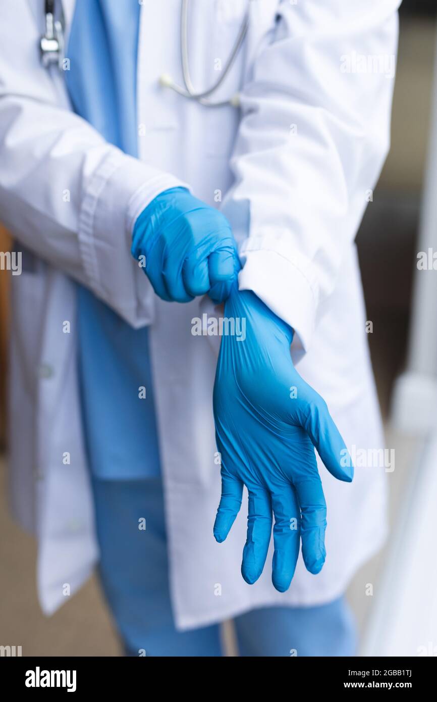 Asian female doctor wearing medical gloves at home before treatment Stock Photo