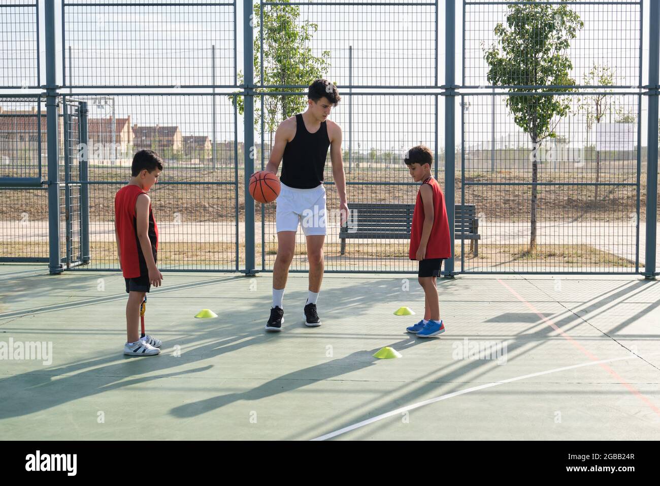 Basketball trainer showing how to play basketball to a two children