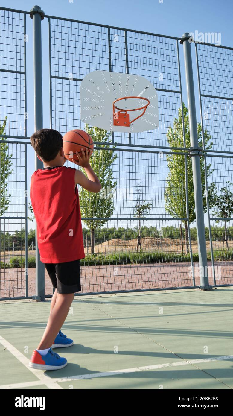 Back view of a basketball kid player throwing the ball to the basket