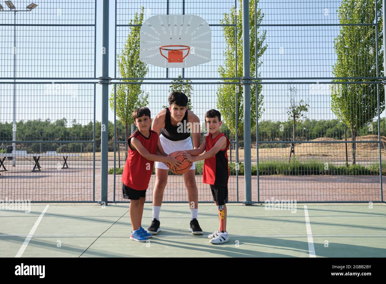 Three brothers looking at camera with a basketball, one has a leg