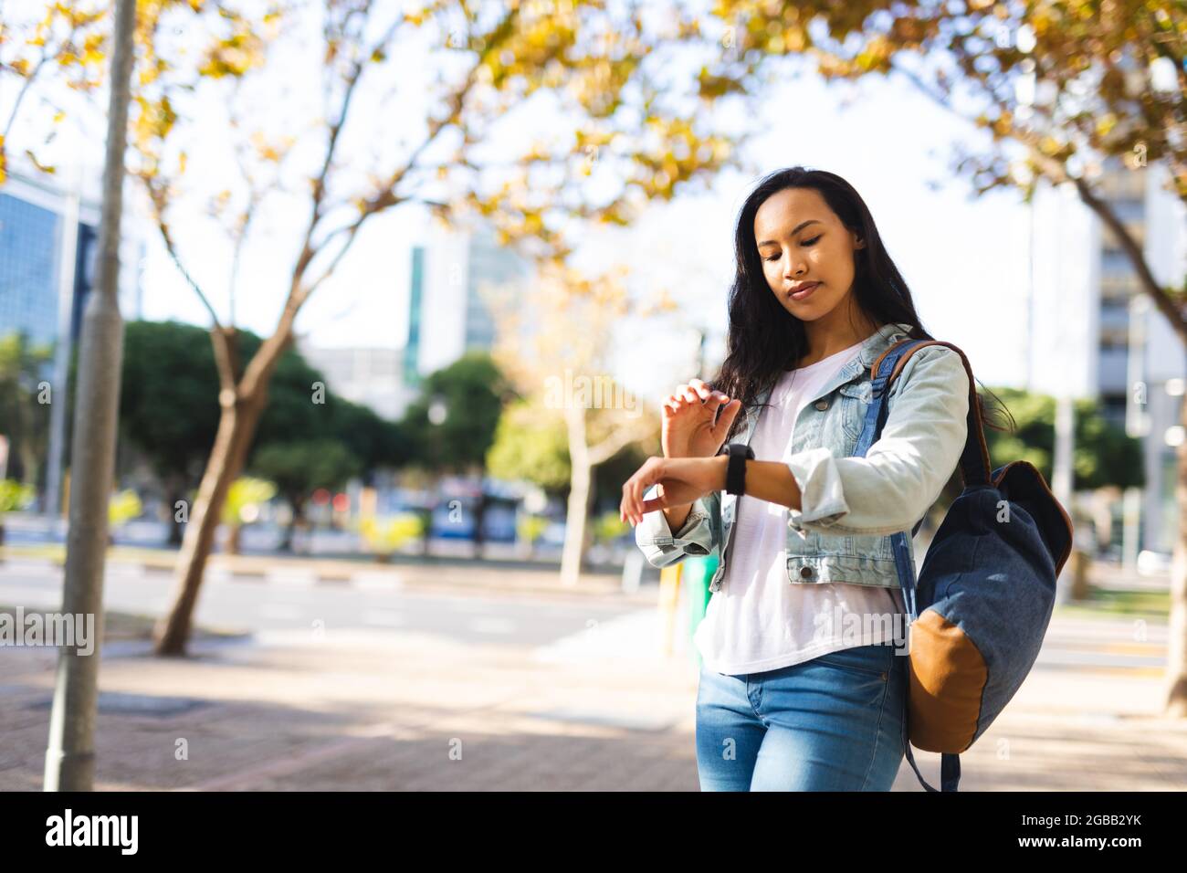 Asian woman checking her smartwatch in sunny park Stock Photo