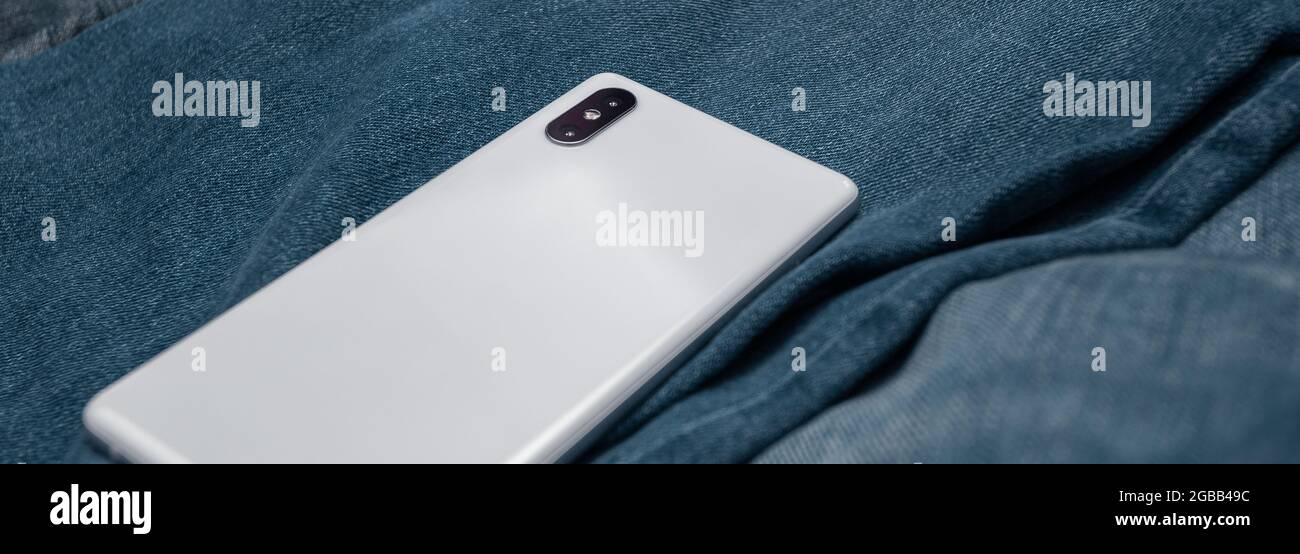 panorama white mobile phone on blue jeans Stock Photo