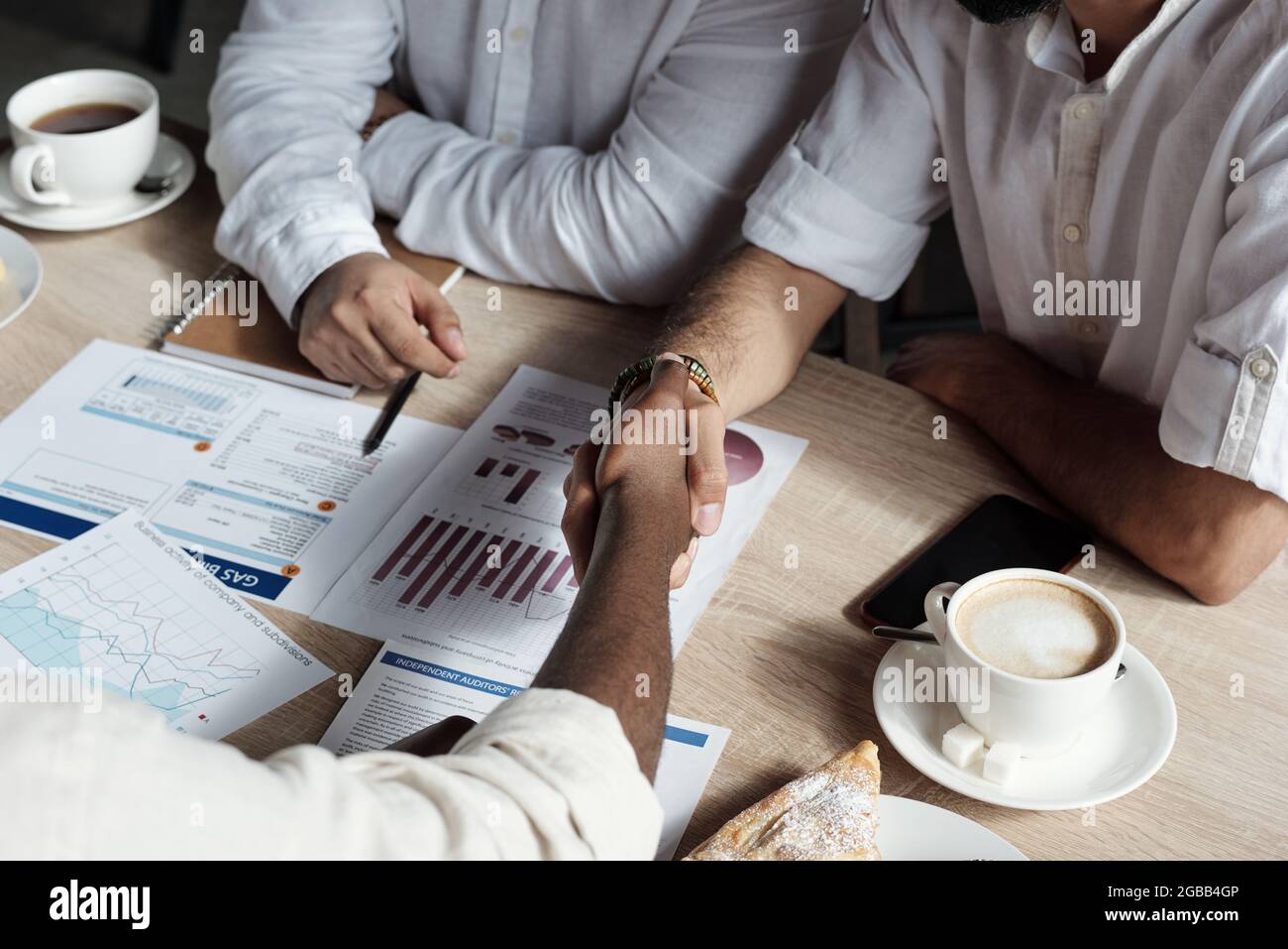 Two Arabic businessmen shaking hands over table while making agreement Stock Photo