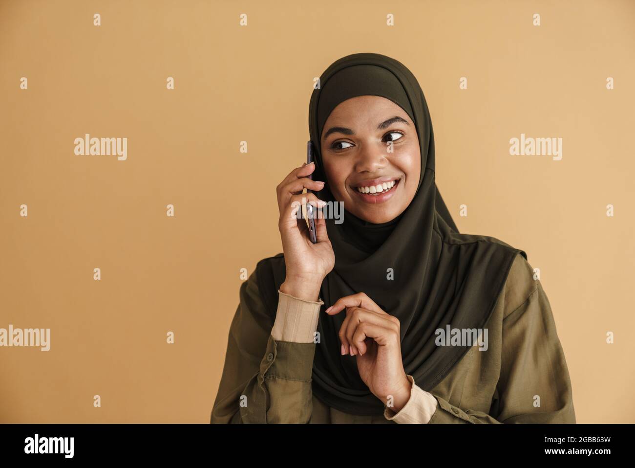Black muslim woman in hijab smiling and talking on mobile phone ...