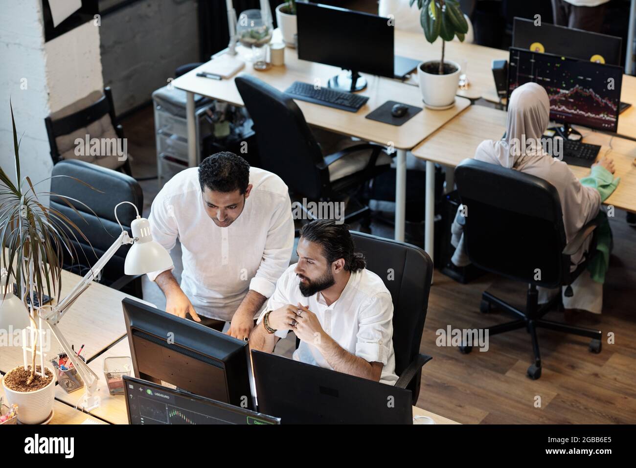 Two businessmen discussing data on computer screen while working in office Stock Photo