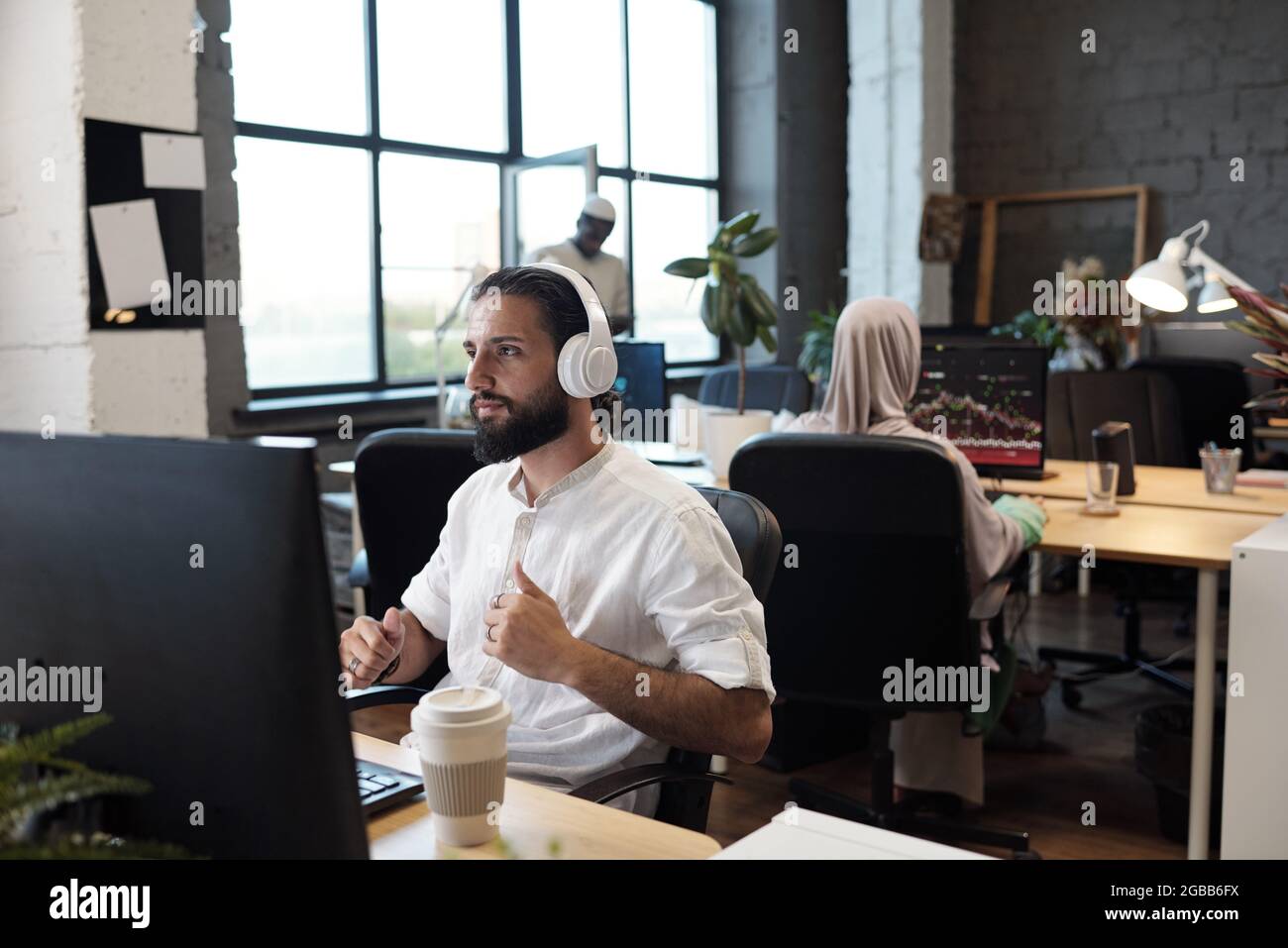 Contemporary young businessman in headphones listening to music during ...