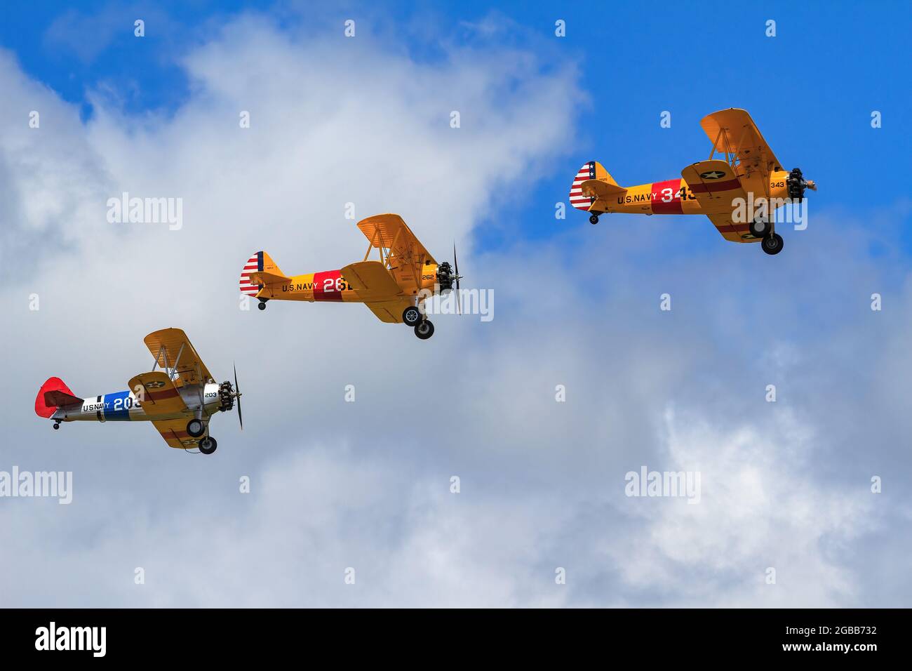 A formation of Boeing-Stearman Model 75 biplanes with historical US Navy markings in the air at an airshow Stock Photo